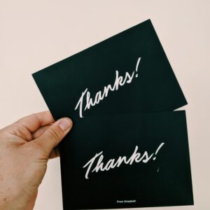 girl holding two thank you card made of black hard paper